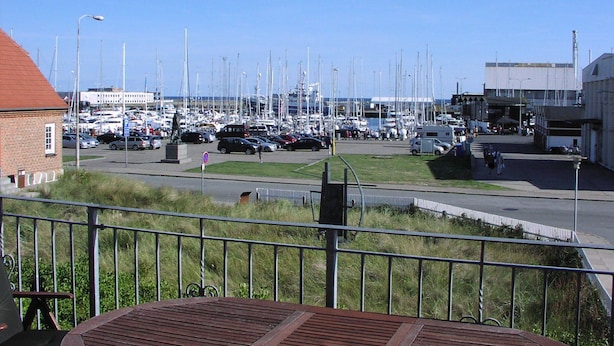 Een jachthaven met boten, een parkeerplaats en een gebouw met een rood dak.