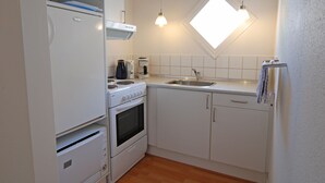 Een kleine keuken met een inbouwoven, een koffiezetapparaat en een spoelbak.