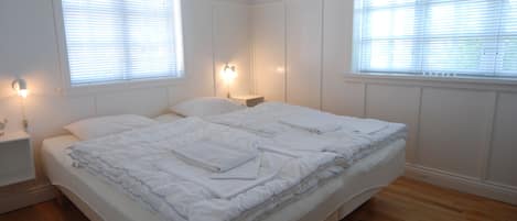 A bedroom with a bed, two bedside tables, and two wall-mounted lamps.