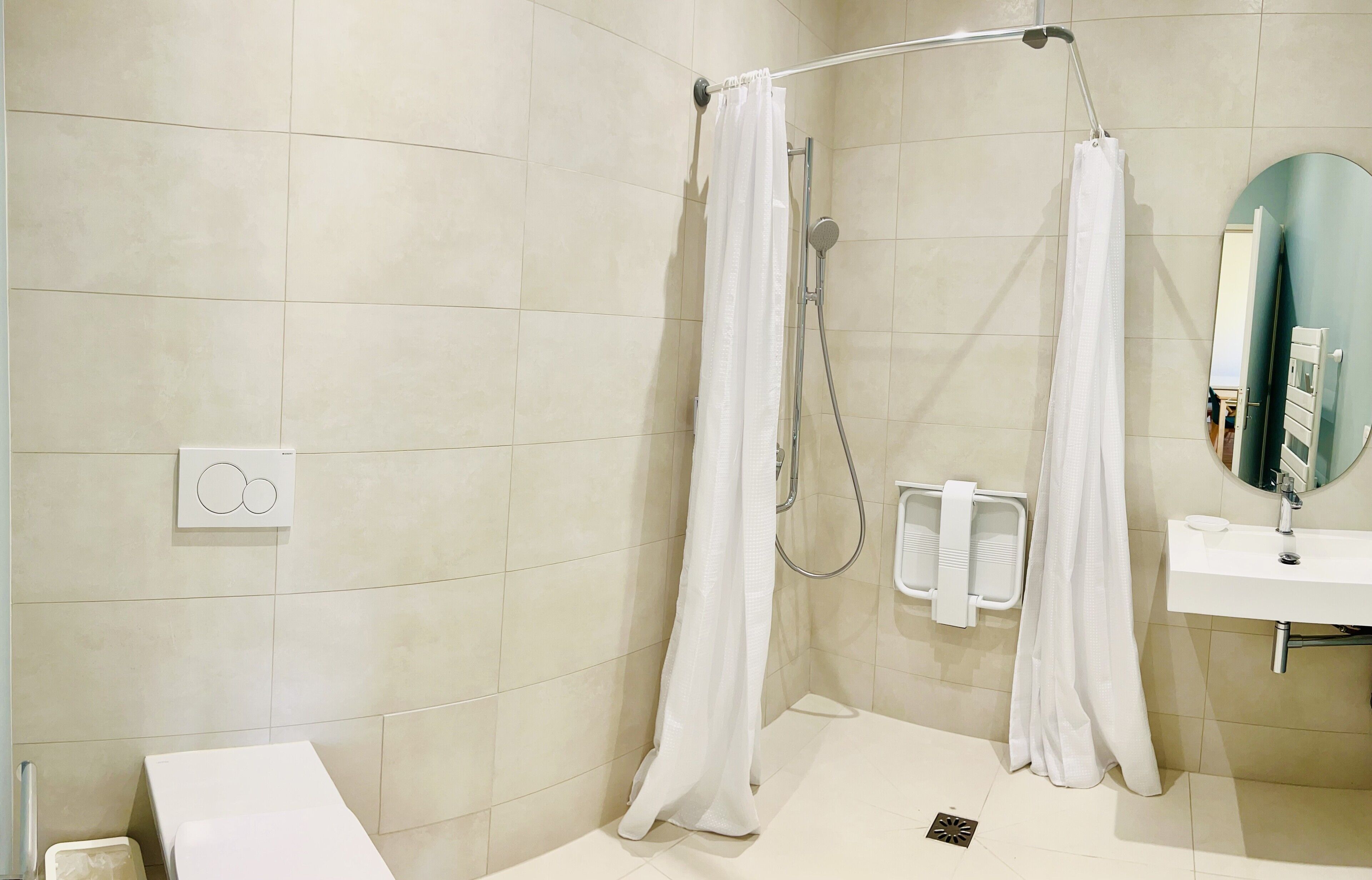 Een moderne badkamer met een douche, wastafel en spiegel.