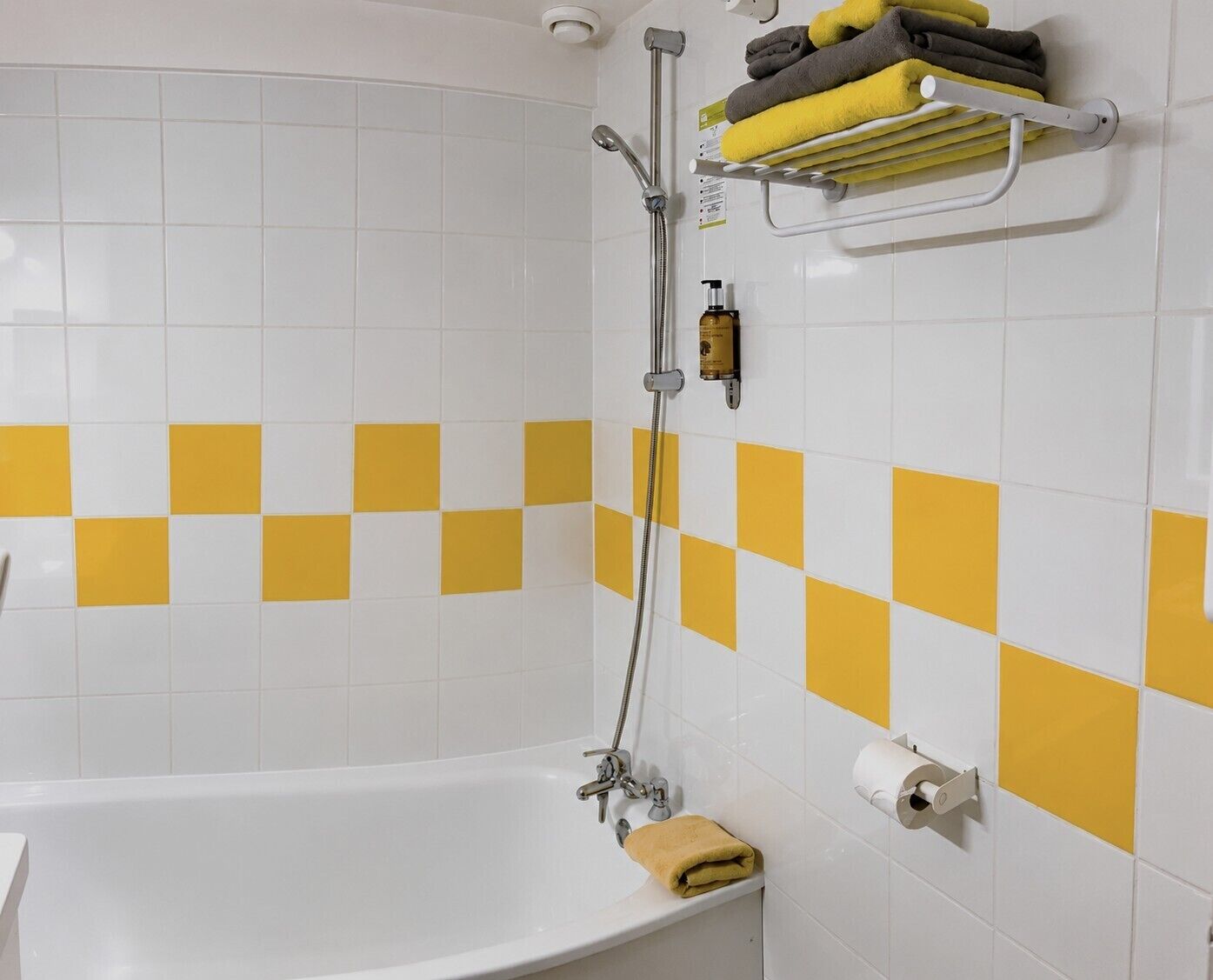 A bathroom with a white bathtub, a shower, and a towel rack with towels.