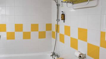 A bathroom with a white bathtub, a shower, and a towel rack with towels.