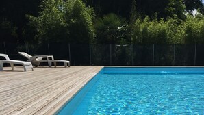 A swimming pool with a wooden deck and lounge chairs. - Résidence Thibaud (Toulouse)