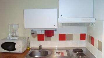 A kitchen with a microwave, sink, stove, and a whiteboard above the counter.