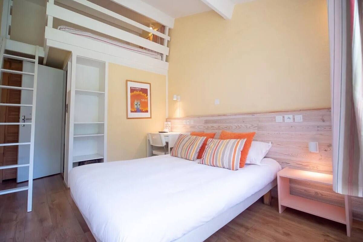 Un dormitorio con una cama individual doble, un escritorio, una silla y una cama con almohadas.