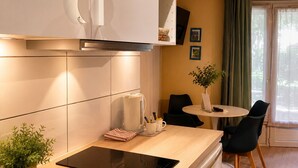 A modern kitchen with a built-in stove, a dining area with a table and chairs, and a view of the outdoors through a window. - Résidence Thibaud (Toulouse)