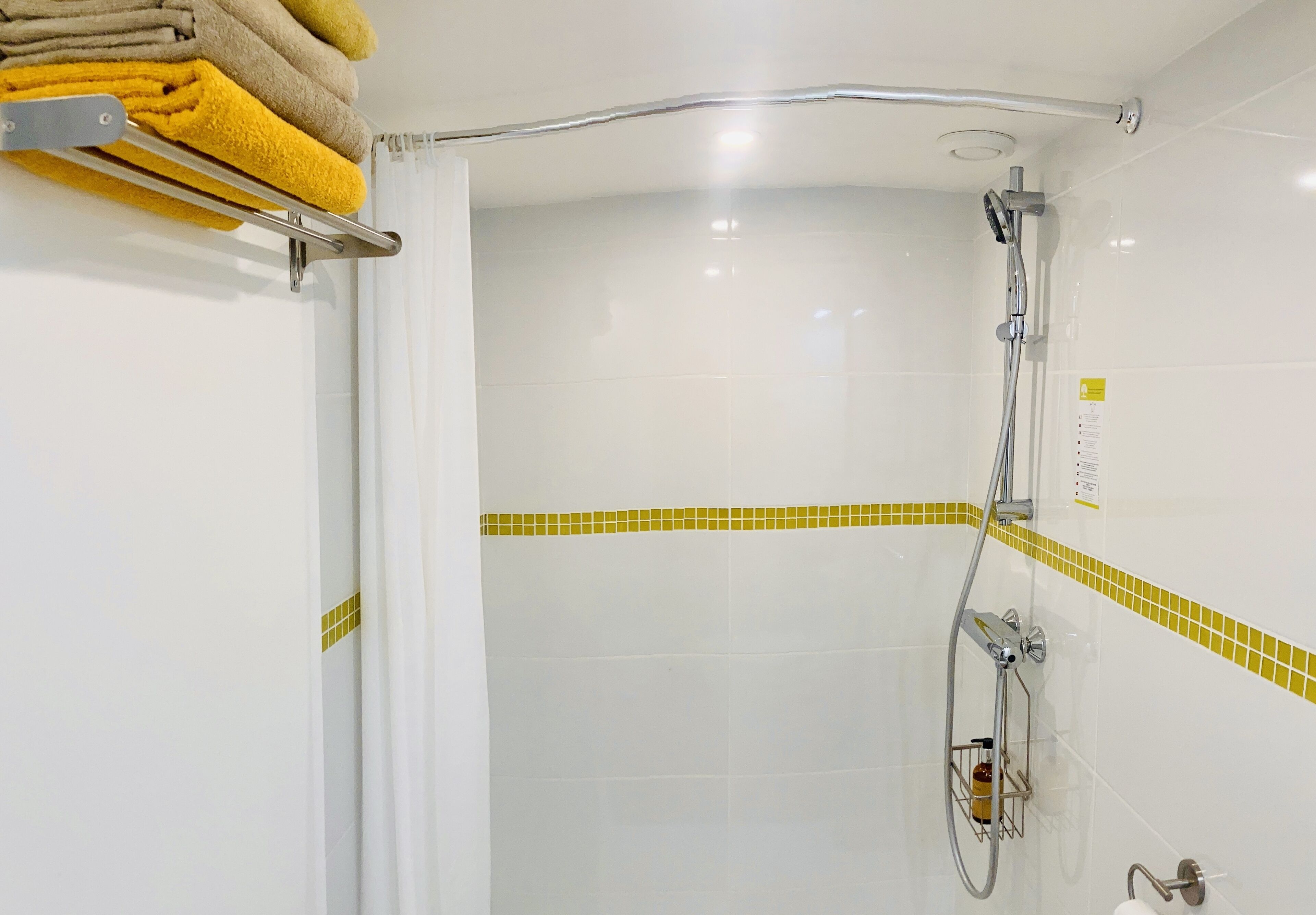 A shower with a handheld showerhead and a wall-mounted faucet.