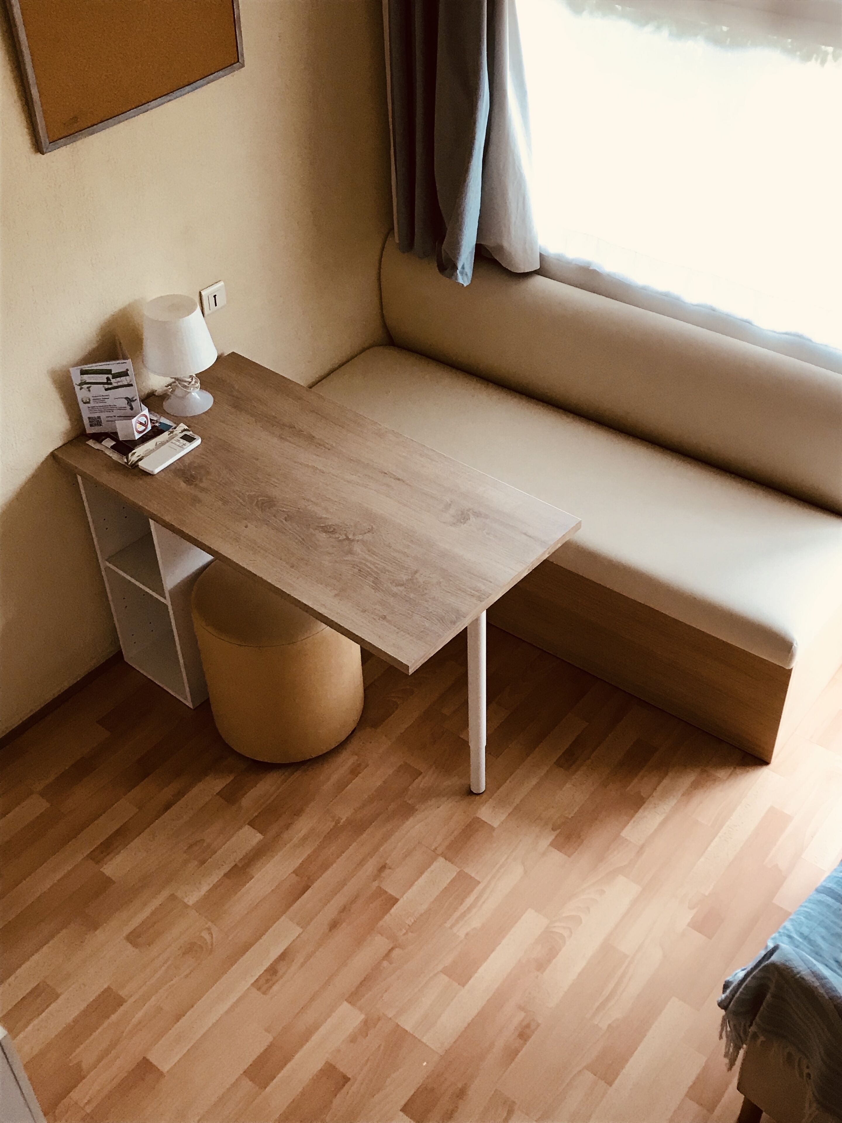 A small, cozy room with a wooden table, a cushioned bench, and a lamp.