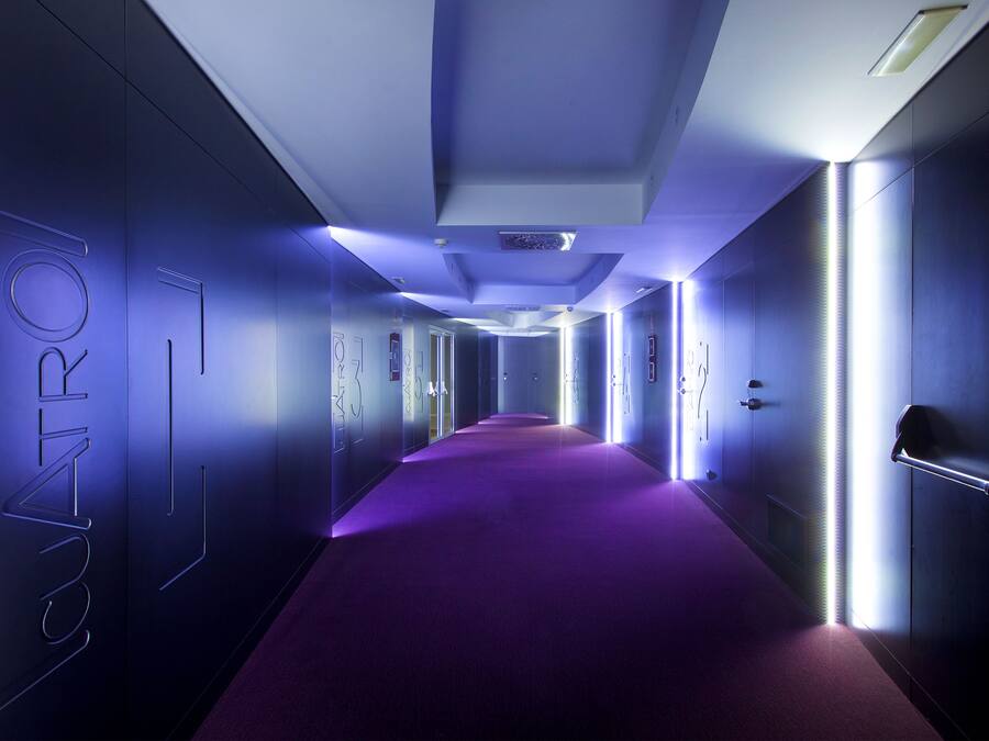 A hallway with a purple carpet, modern lighting, and a wall with the word "CONTRO" visible.