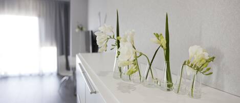A modern bathroom with white fixtures and a row of clear glass vases with white flowers on a white countertop.