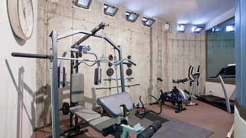 Een sportschool met trainingsapparatuur, een klok en ramen.