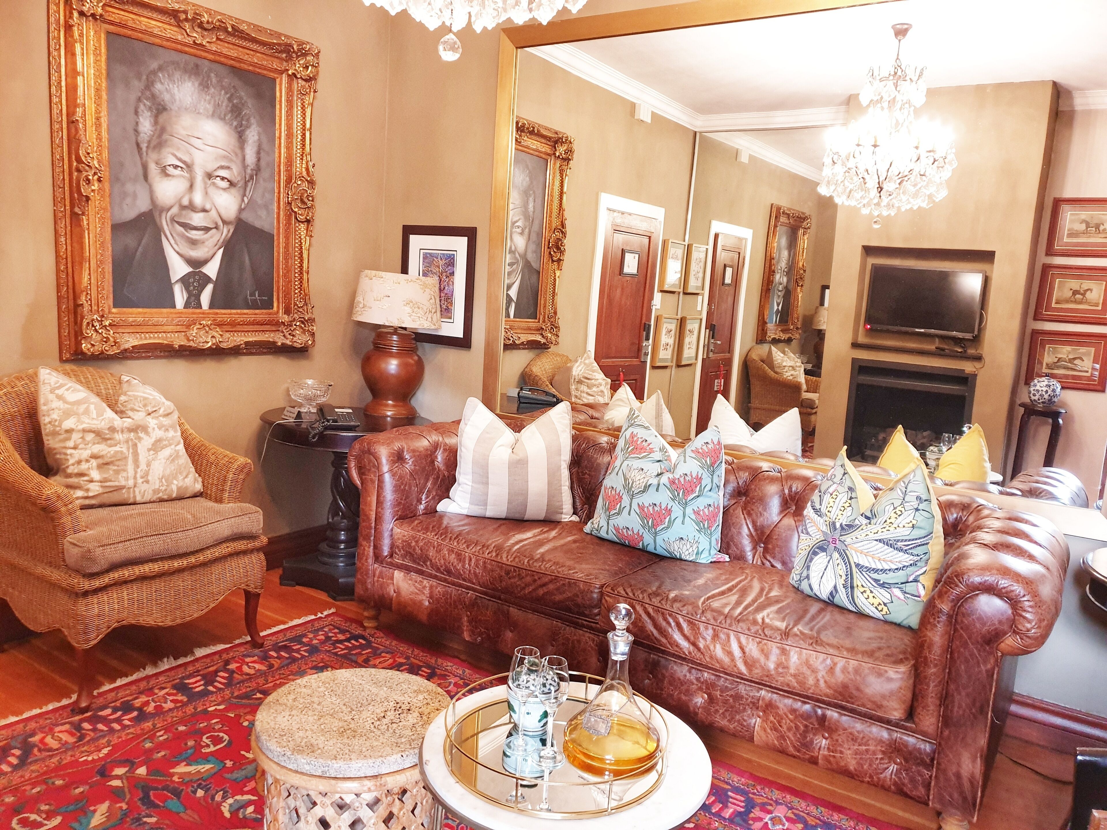 A living room with a brown leather sofa, wicker armchair, and a patterned rug.