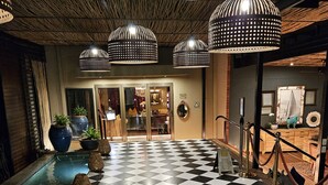A checkered floor leading to a pool area with potted plants and a mirror on the wall. - The Residence Boutique Hotel (Johannesburg)
