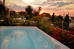 A swimming pool with a sunset view, surrounded by lush greenery and a mosque in the background.
