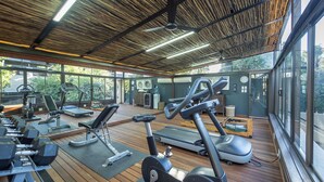 A gym with various exercise equipment, large windows, and a wooden ceiling. - The Residence Boutique Hotel (Johannesburg)