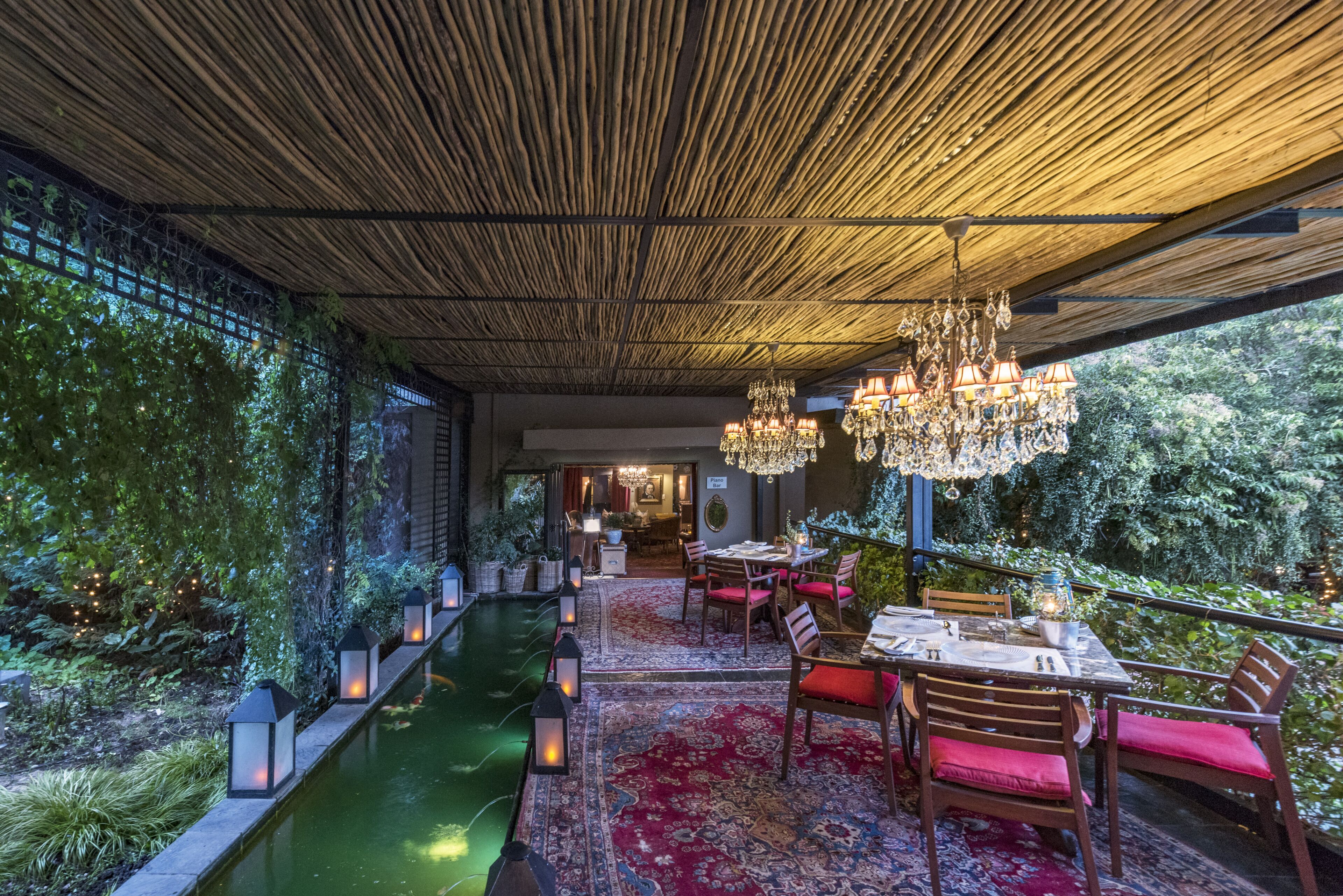 Un comedor interior con piscina, techo de madera y sillas rojas.