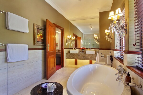 A spacious bathroom with a large bathtub, a vanity with a mirror, and a shower area.