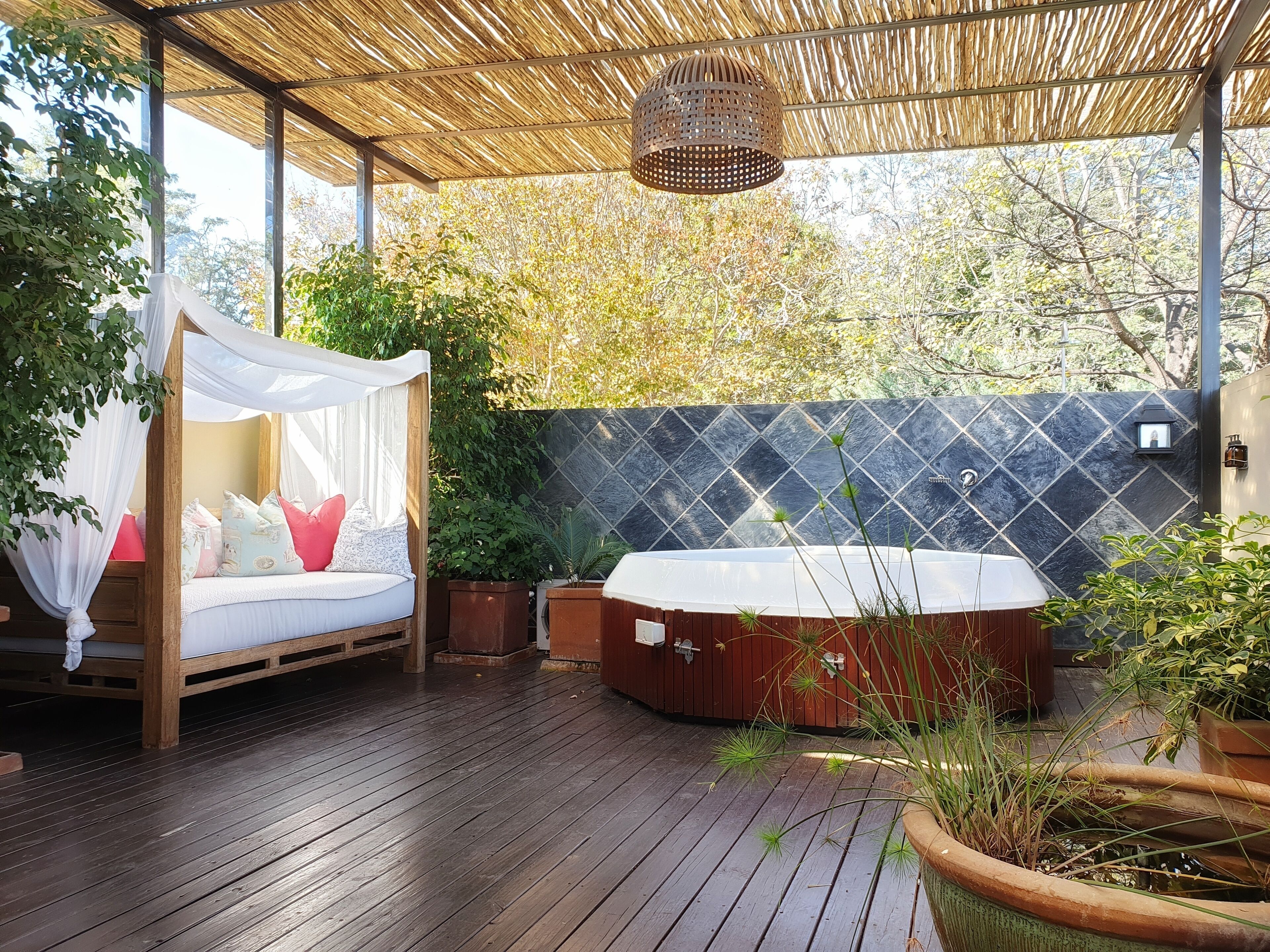 Eine Holzterrasse mit einem Himmelbett und einer Whirlwanne.