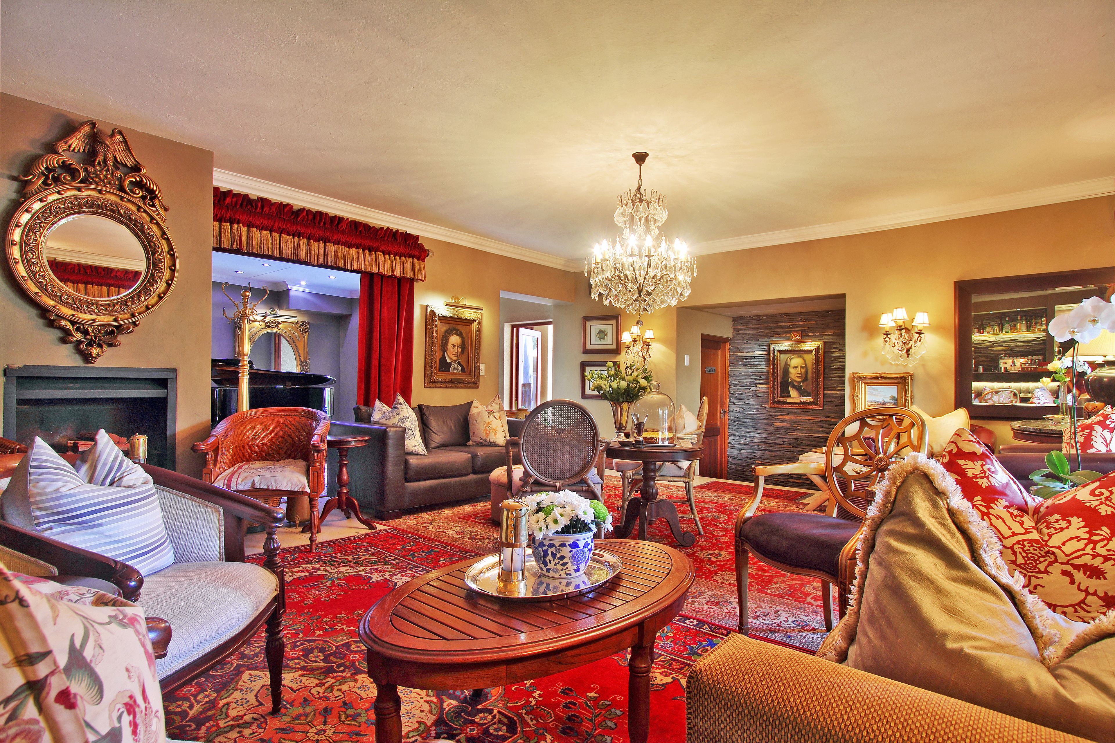 A well-furnished living room with a fireplace, a chandelier, and a red carpet.