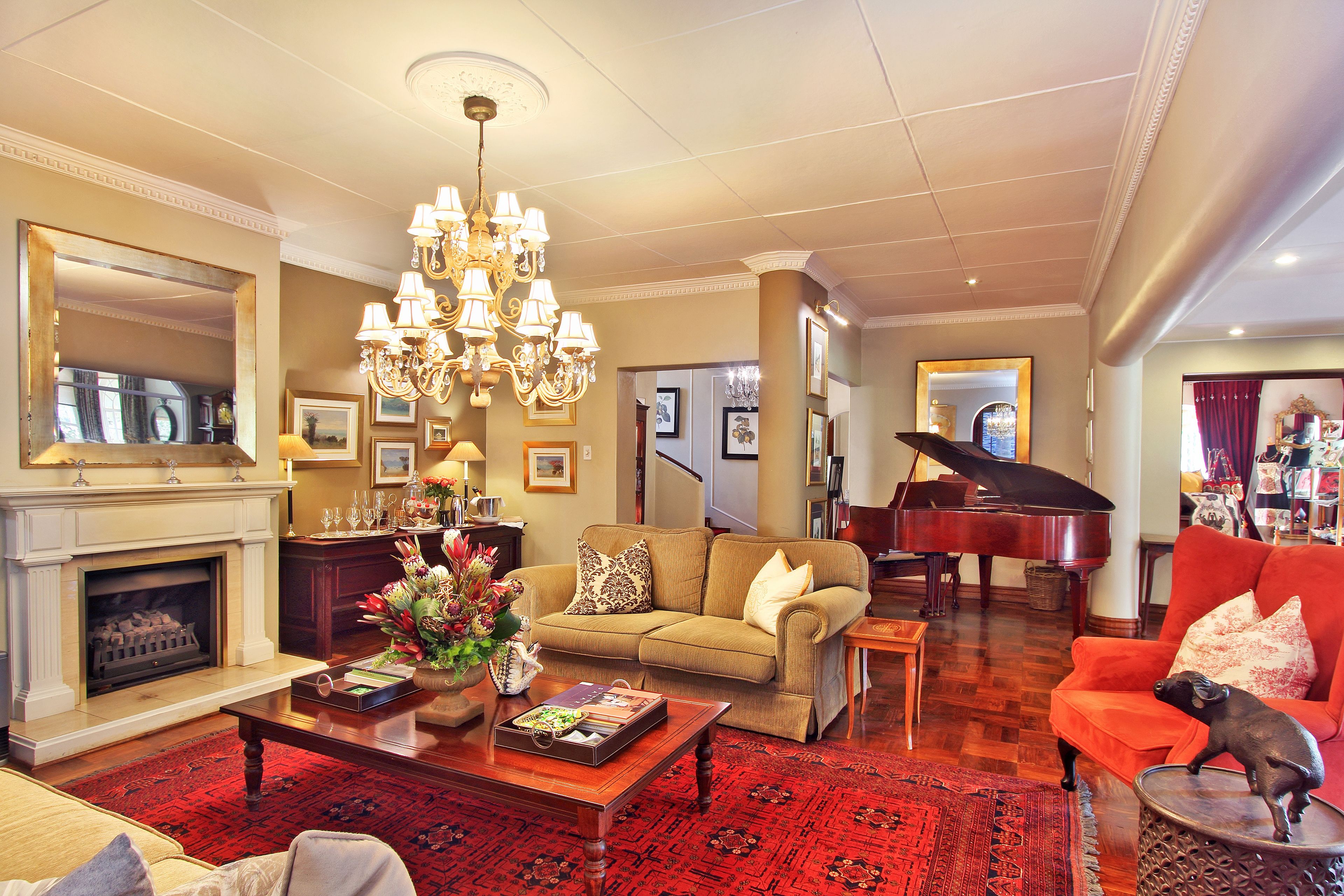 A spacious living room with a grand piano, a fireplace, and a chandelier.