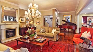 A spacious living room with a grand piano, a fireplace, and a chandelier.