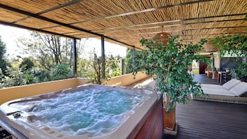 Un jacuzzi bajo techo de bambú, rodeado de madera y follaje.