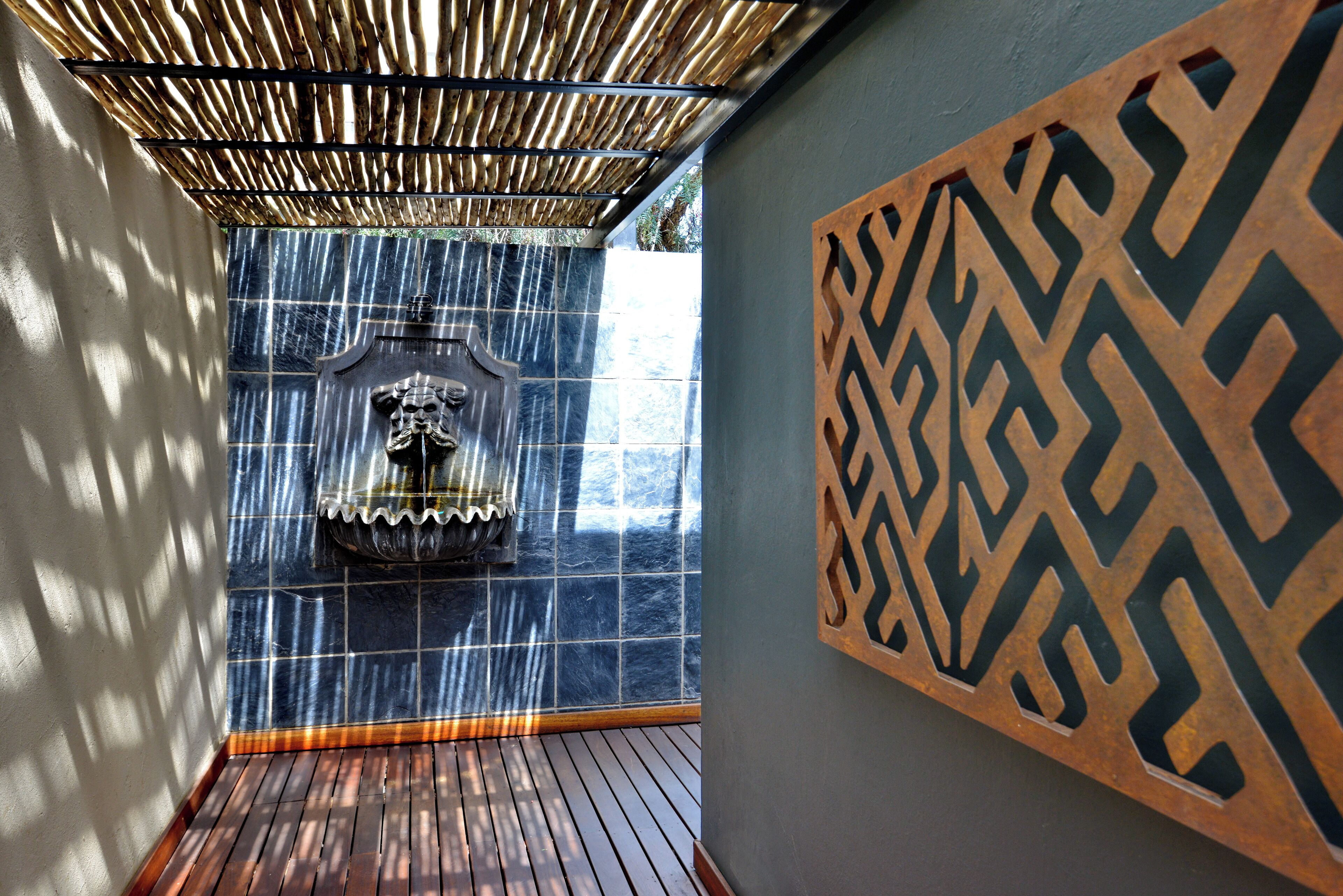 A room with a wooden floor, a decorative wall panel, and a water feature with a statue.