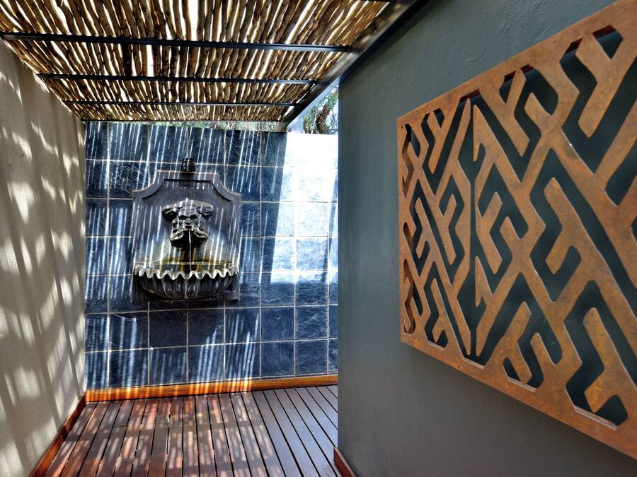 A room with a wooden floor, a decorative wall panel, and a water feature with a statue.