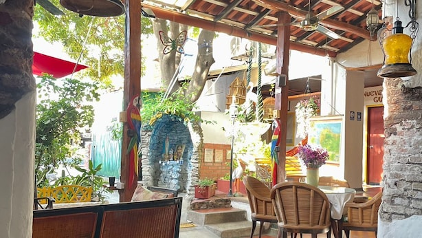 Un restaurante con mesas y sillas de madera, una pared de piedra y faroles colgantes.