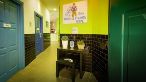 Un pasillo con puertas azules, una recepción y un cartel anunciando la Estación Juvenil Roma.