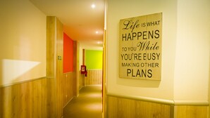 Un pasillo con paneles de madera y un cartel en la pared que dice: "La vida es lo que ocurre mientras estás ocupado haciendo otros planes." 