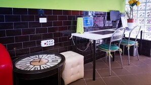 Un restaurante con una salpicadera de azulejos negros, una mesa blanca y sillas con cojines verdes.