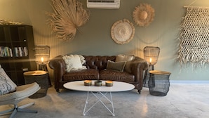 Een gezellige woonkamer met een leren bank, een ronde salontafel en decoratieve wandversieringen.