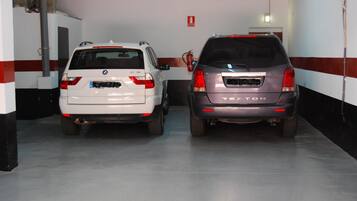 Two cars parked in a garage with a red and white striped wall.