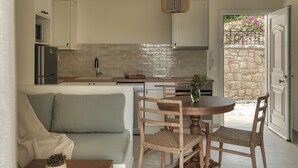 Una cuina moderna amb armaris blancs, un frontissó de maó i una zona de menjador amb taula rodona i cadires de vimet.