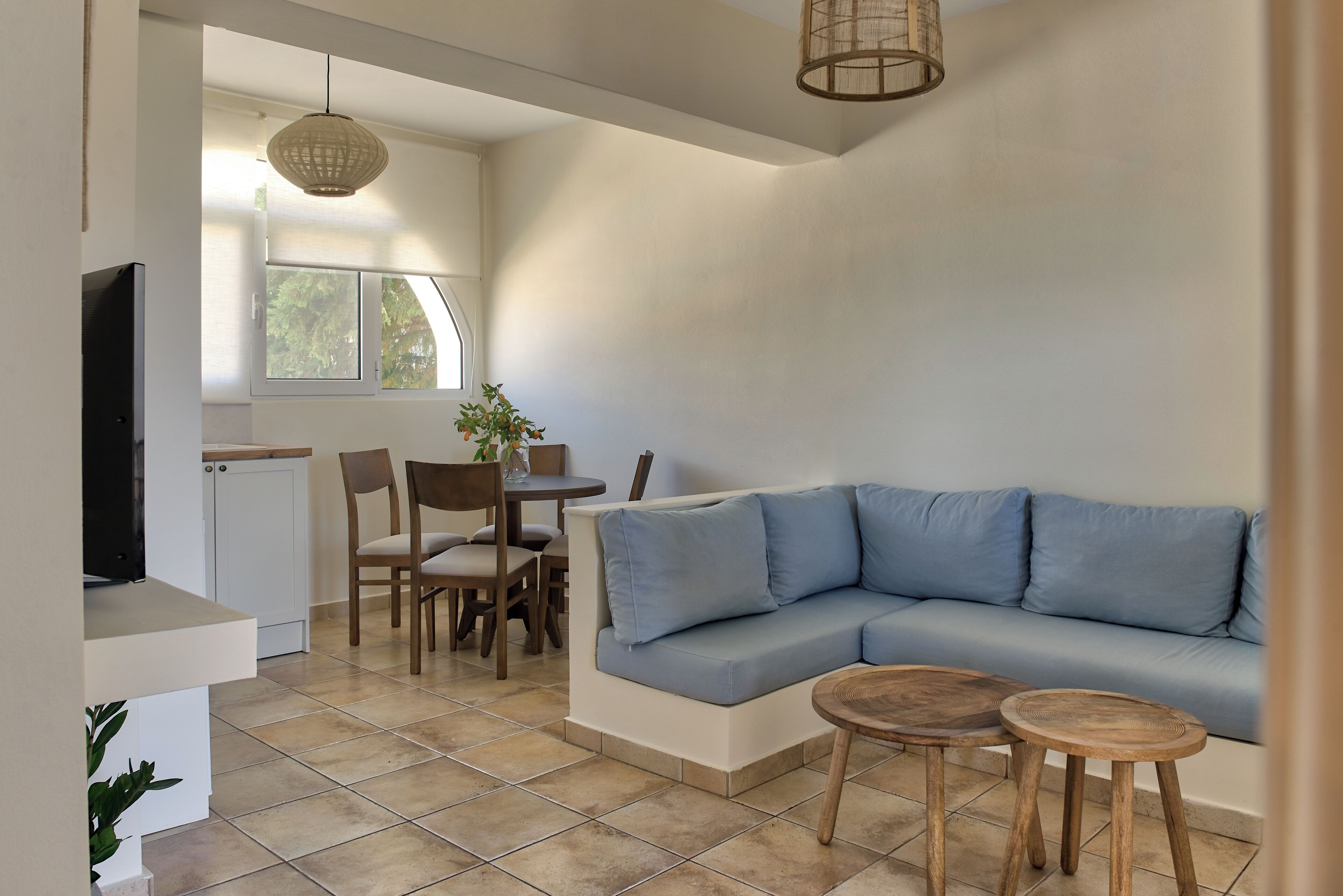 Ein modernes Wohnzimmer mit einem blauen Sofa, Holzstühlen, einem kleinen Tisch und einem Fernseher.