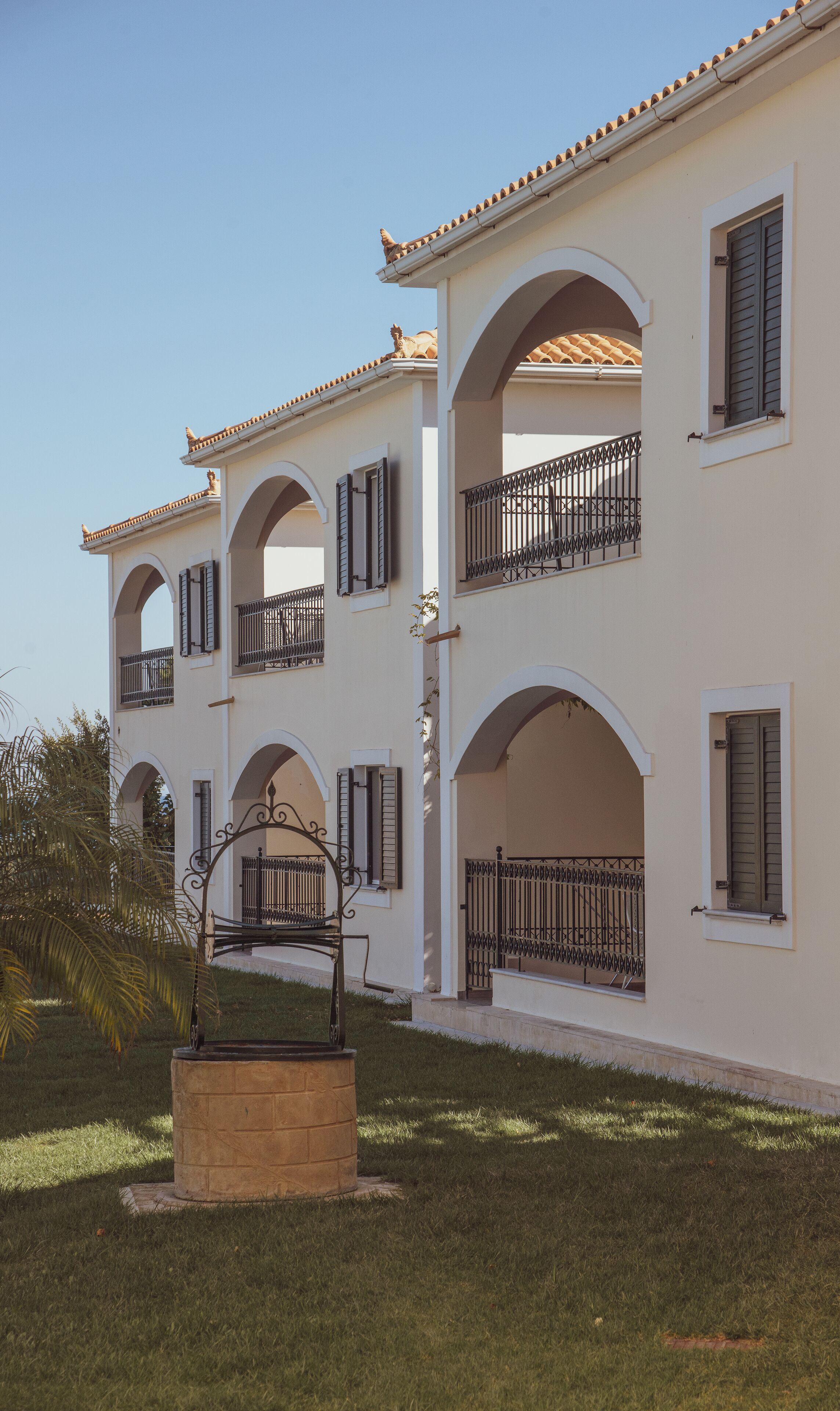 A multi-story building with arched balconies, a central courtyard, and a well-maintained lawn.