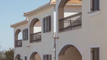 A multi-story building with arched balconies, a central courtyard, and a well-maintained lawn.