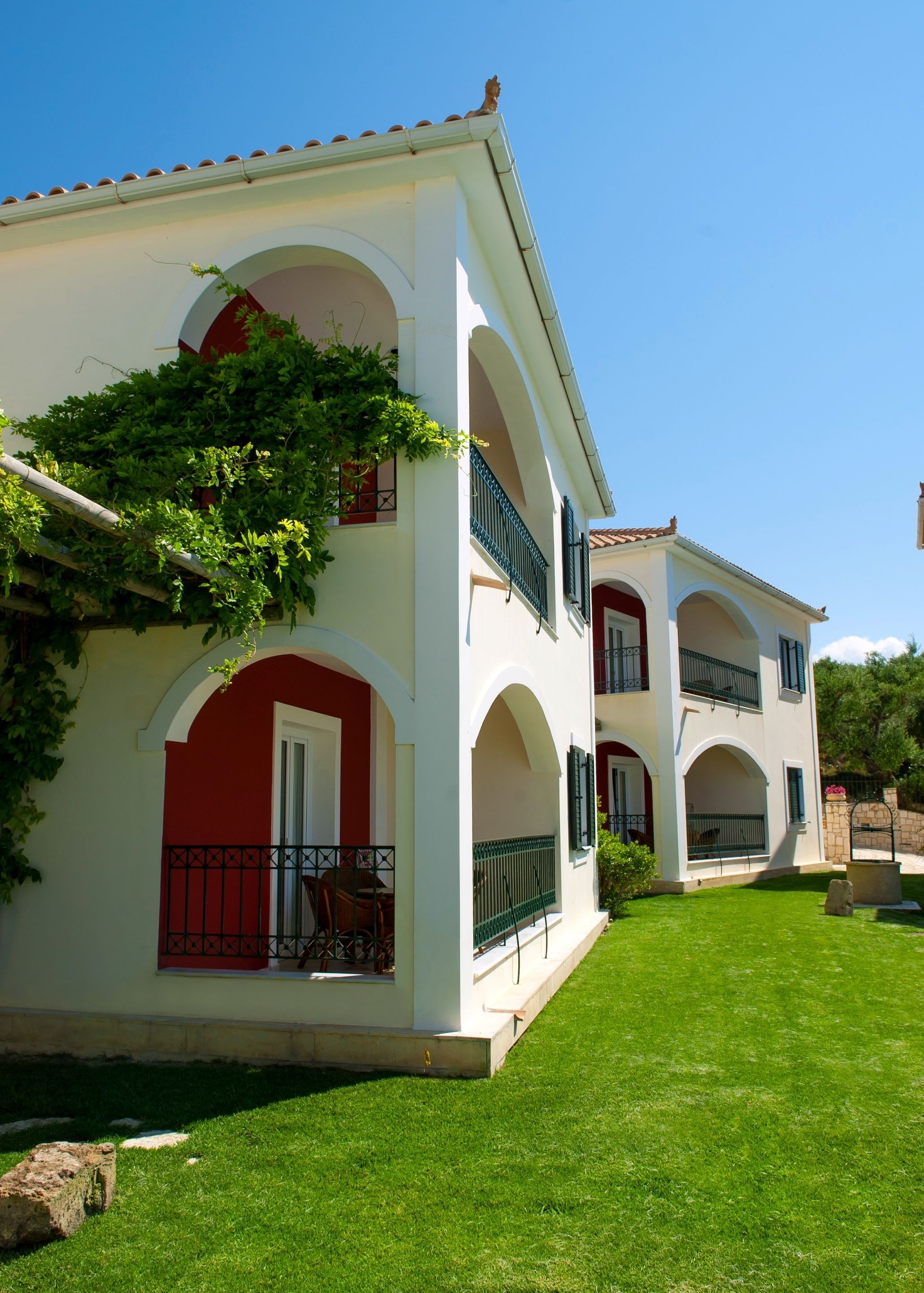A two-story building with a white facade, red accents, and green balconies.