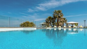 Una piscina de blau clar amb gandules i palmeres.