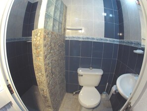 A bathroom with a toilet, sink, and shower area. - Hotel Tayrona Dive Center (Santa Marta)