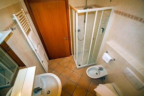 A bathroom with a shower enclosure, a sink, a bidet, and a toilet.