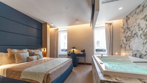 Un dormitorio moderno con una cama grande, un escritorio y una bañera de hidromasaje.