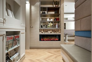A modern living room with a built-in fireplace, a bookshelf, and a seating area. - San Carlo Suite (Rome)