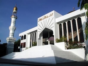A mosque with a minaret and a white facade with Arabic calligraphy. - Kaani Lodge (Malé)
