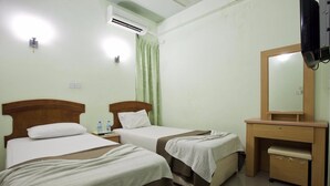 A hotel room with two beds, a wooden desk, a mirror, and an air conditioning unit. - Kaani Lodge (Malé)