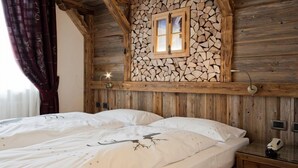 Un dormitorio tipo cabaña de madera con cama, mesita de noche y lámpara de pared.
