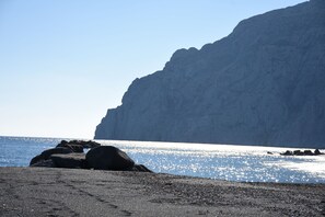 Am Strand, schwarzer Sandstrand, Liegestühle, Sonnenschirme