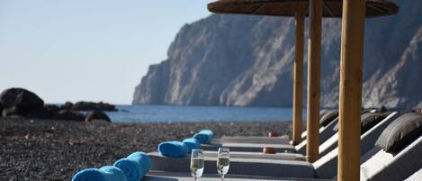 On the beach, black sand, sun-loungers, beach umbrellas