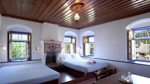 Quarto com duas camas, lareira e janelas amplas.